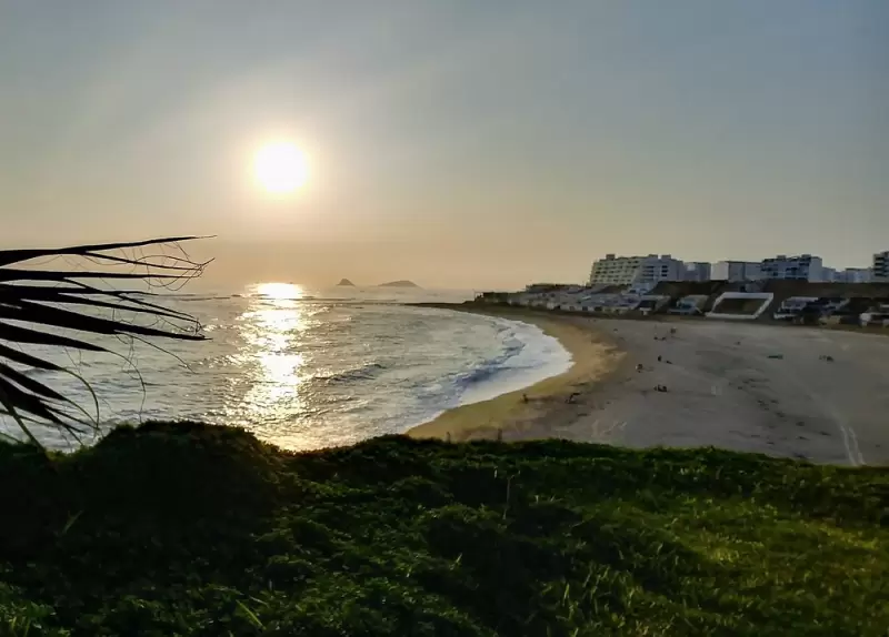 Vista general de Playa Caballero durante el verano, con surfistas y visitantes en la bahía
