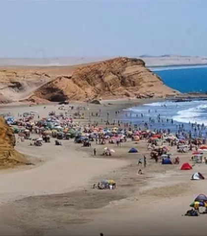 Vista panor�mica de Playa El Colorado en Huacho, con visitantes bajo sombrillas y oleaje suave sobre la arena dorada