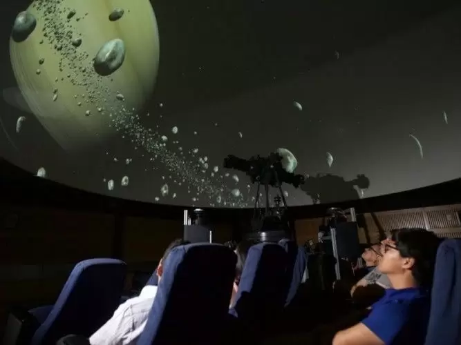 Proyección digital immersiva dentro del domo del planetario, mostrando constelaciones y sistemas planetarios durante una función.