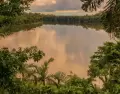 Vista del Lago Sandoval reflejando el verde vibrante de la selva y un cielo sereno al amanecer o atardecer.