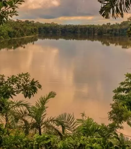 Vista del Lago Sandoval reflejando el verde vibrante de la selva y un cielo sereno al amanecer o atardecer.