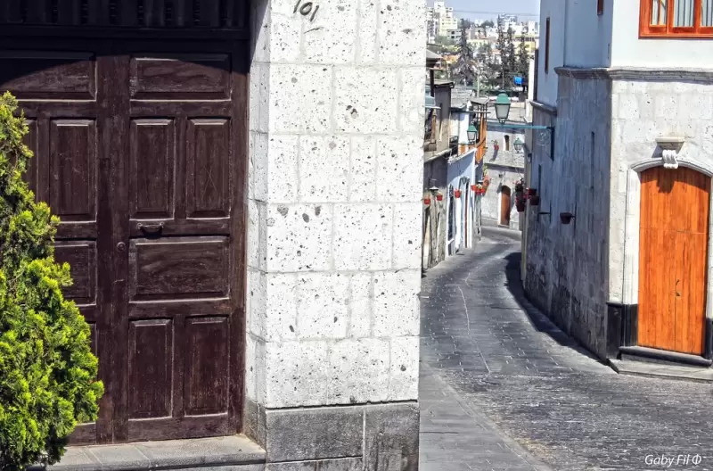 Desde una esquina del barrio se puede apreciar el entramado de calles coloniales con el perfil urbano y el volcán en el horizonte.