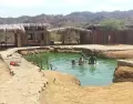 Poza de agua termal en Zorritos con vapor y entorno natural.
