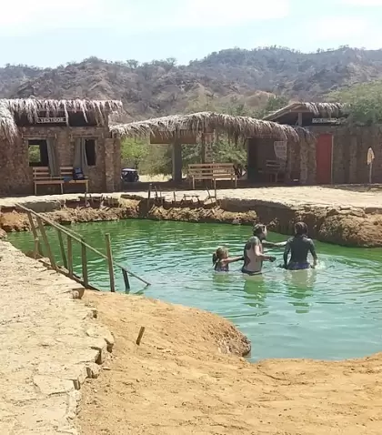 Poza de agua termal en Zorritos con vapor y entorno natural.