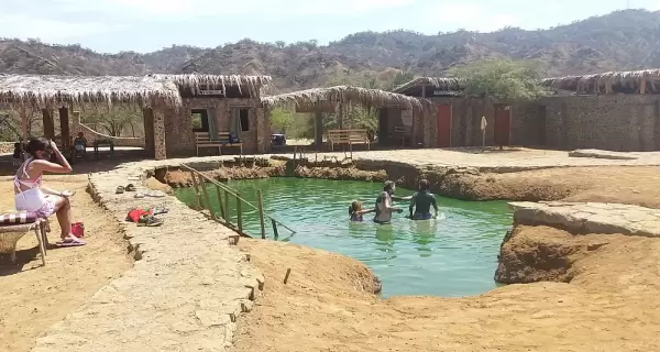 Poza de agua termal en Zorritos con vapor y entorno natural.