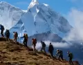 Senderistas caminando por una ruta altoandina de Huaraz, con nevados de la Cordillera Blanca y cielo despejado de julio.