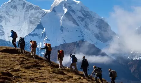 Senderistas caminando por una ruta altoandina de Huaraz, con nevados de la Cordillera Blanca y cielo despejado de julio.