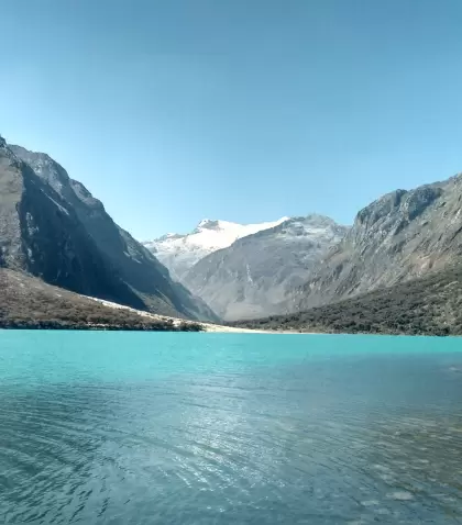 Laguna Llanganuco en julio, con agua turquesa, bosque andino y nevados de la Cordillera Blanca.