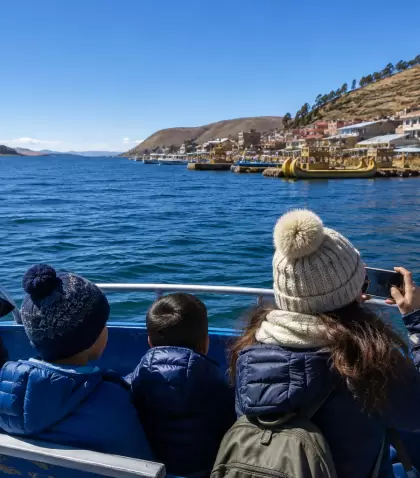 Viajeros abrigados navegando por el Lago Titicaca en julio-